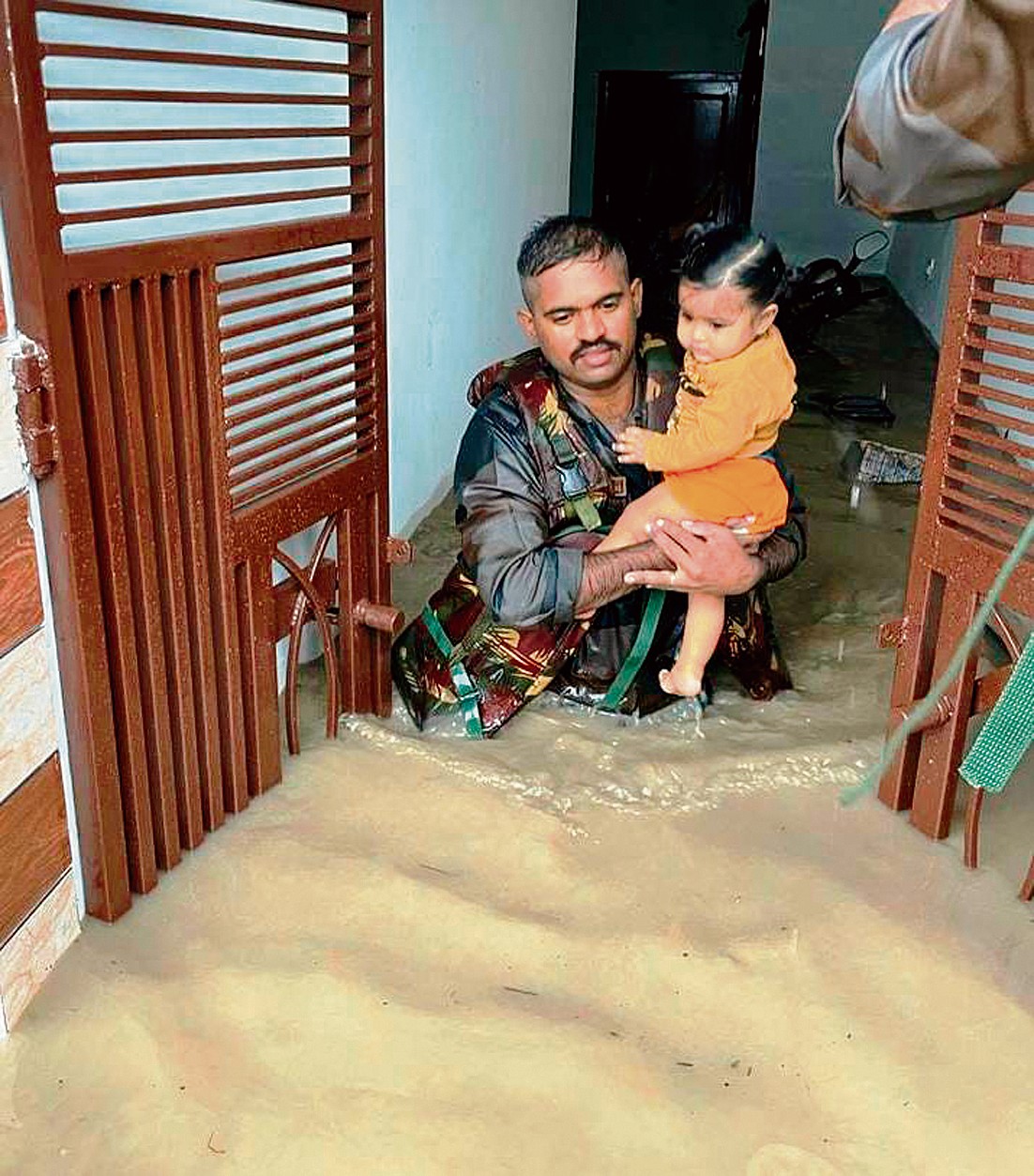 ਰਾਜਪੁਰਾ ਨੇੜੇ ਘਰ ਵਿੱਚ ਆਏ ਪਾਣੀ ’ਚੋਂ ਇਕ ਬੱਚੇ ਨੂੰ ਕੱਢ ਕੇ ਬਾਹਰ ਲਿਆਉਂਦਾ ਹੋਇਆ ਫੌਜੀ।