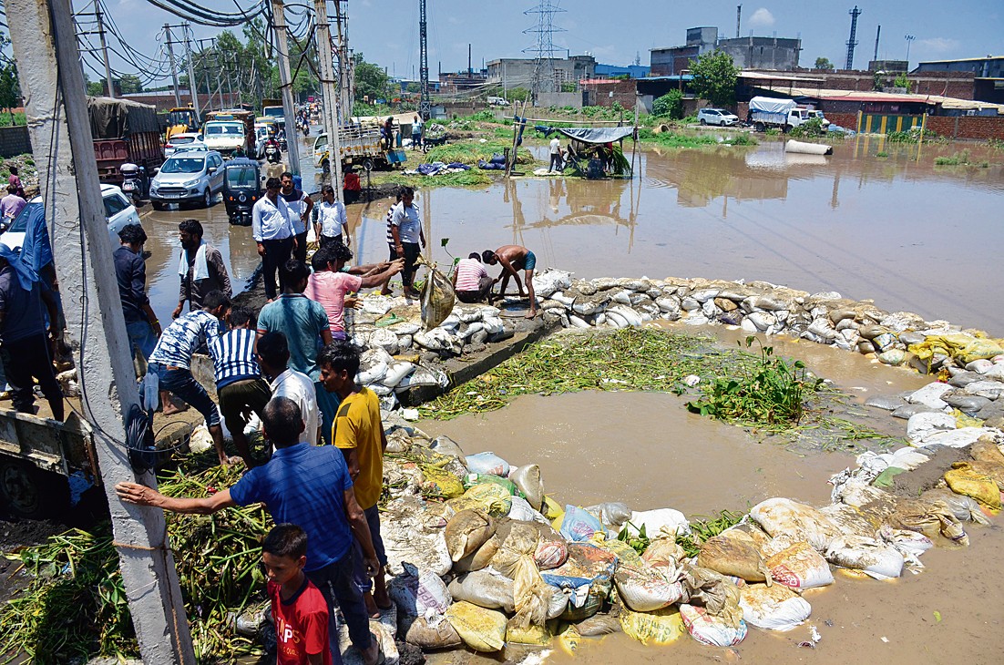 ਤਾਜਪੁਰ ਰੋਡ ’ਤੇ ਬੁੱਢੇ ਨਾਲੇ ਦੇ ਪਾਣੀ ਨੂੰ ਰੇਤੇ ਦੀਆਂ ਬੋਰੀਆਂ ਲਗਾ ਕੇ ਰੋਕਦੇ ਹੋਏ ਲੋਕ।